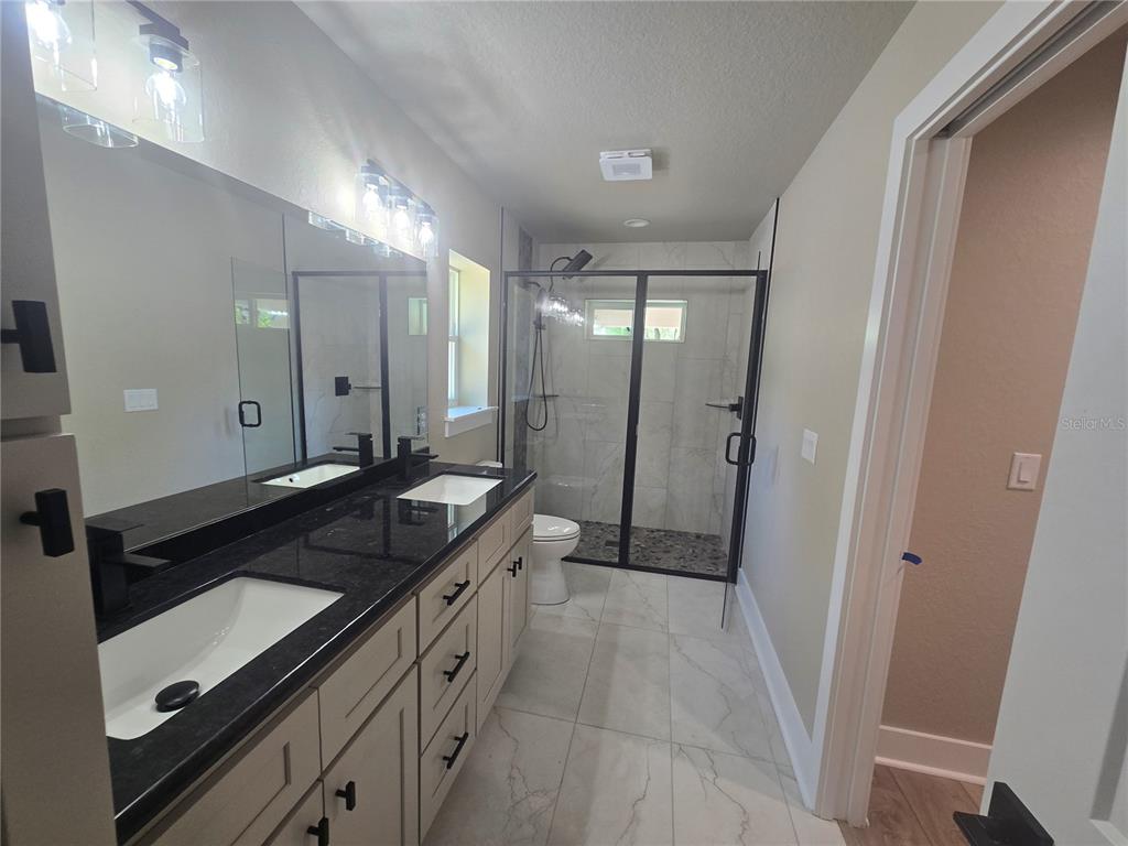 8541 Northeast 105th Avenue Bronson, FL 32621 - Photo 18 of 20 a spacious bathroom with a granite countertop sink a mirror and a shower