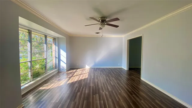 a view of empty room with wooden floor and fan