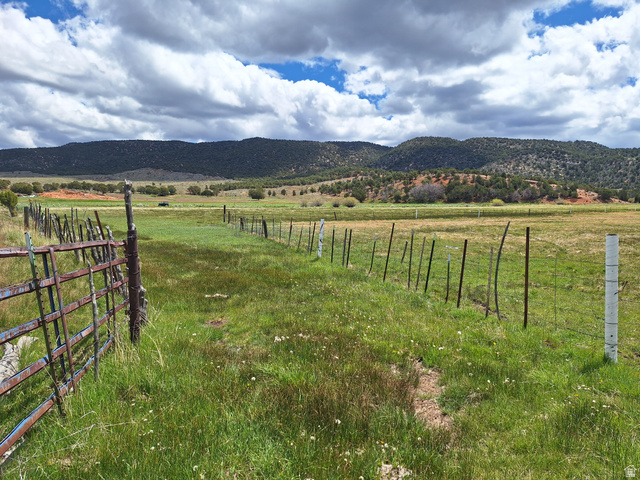 Expansive open fields with natural landscaping, bordered by a rustic wire fence and metal gate