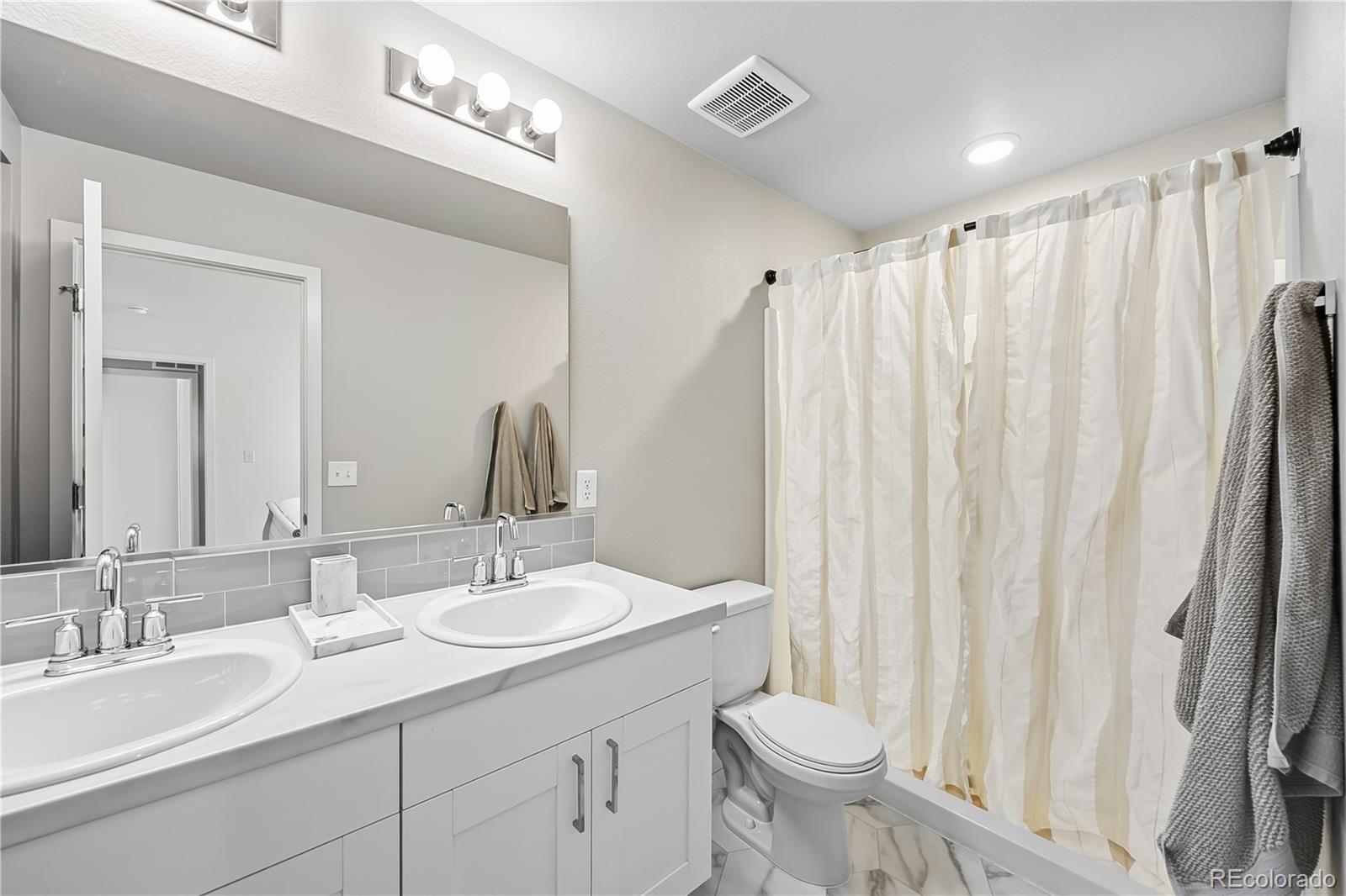 669 South Hoover Avenue Fort Lupton, CO 80621 - Photo 14 of 24 a bathroom with a double vanity sink toilet and a mirror