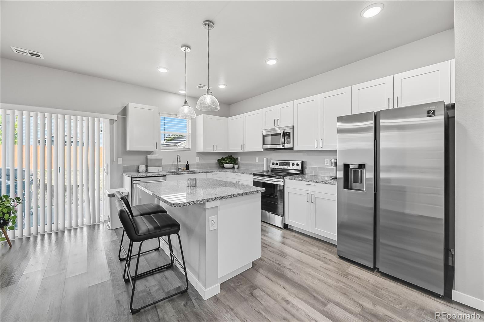 669 South Hoover Avenue Fort Lupton, CO 80621 - Photo 7 of 24 a kitchen with stainless steel appliances granite countertop a refrigerator a sink dishwasher a stove and white cabinets with wooden floor