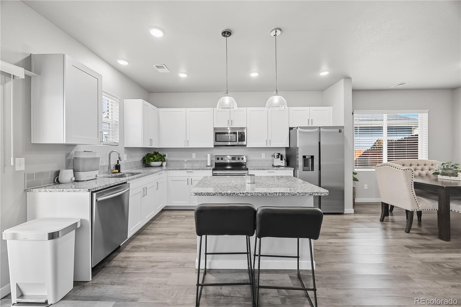 669 South Hoover Avenue Fort Lupton, CO 80621 - Photo 8 of 24 a kitchen with stainless steel appliances granite countertop a stove top oven a refrigerator a sink and chairs