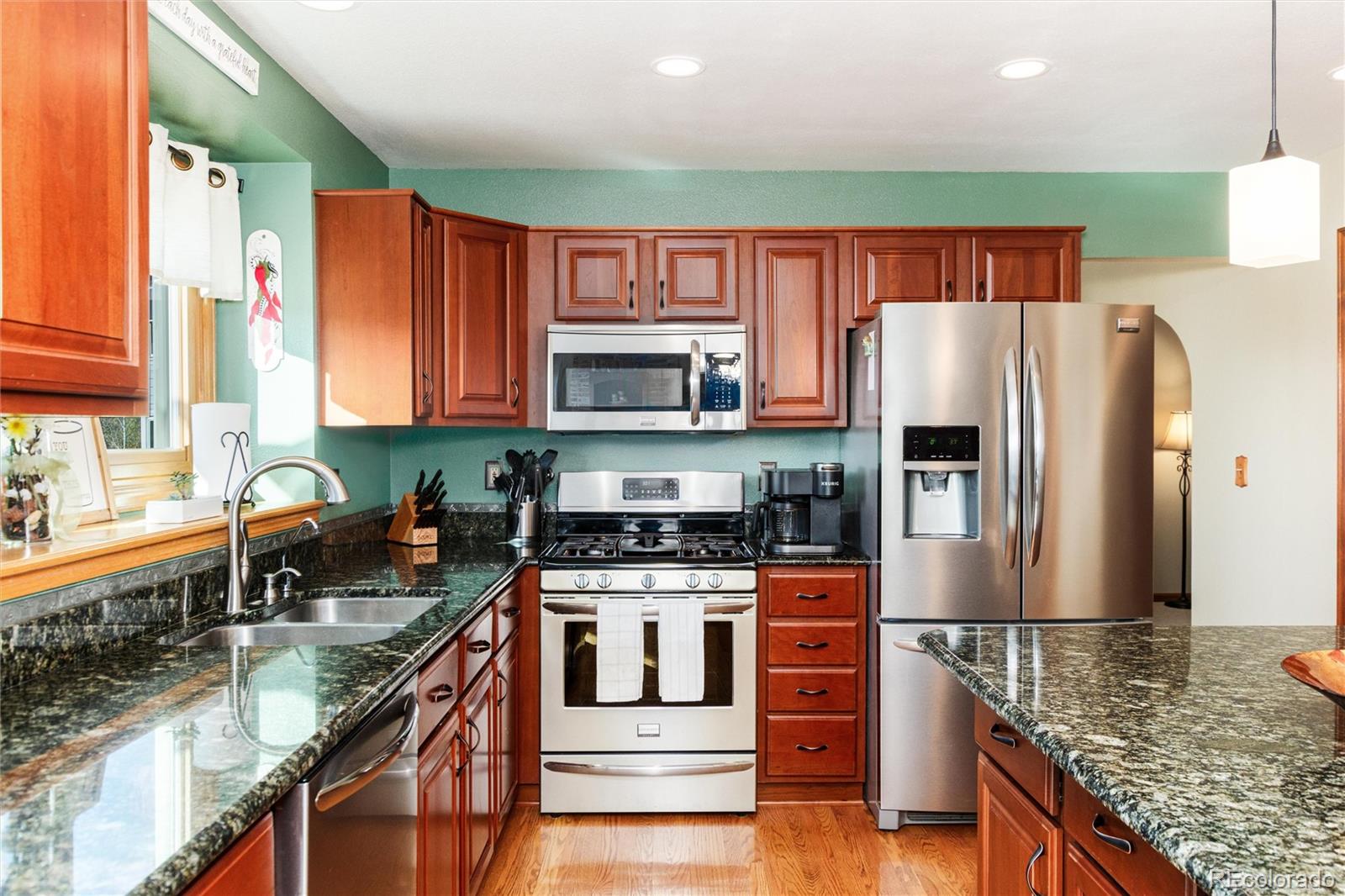 9635 Cherryvale Drive Highlands Ranch, CO 80126 - Photo 12 of 46 a kitchen with stainless steel appliances granite countertop a stove top oven a sink dishwasher a refrigerator and a microwave