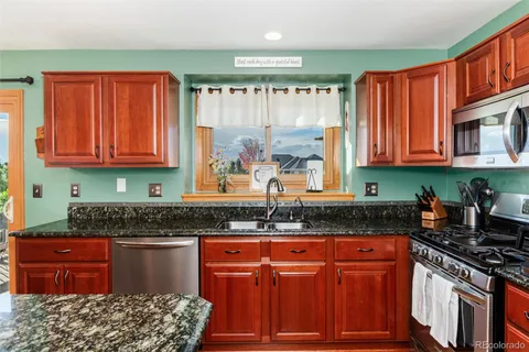 a kitchen with stainless steel appliances granite countertop a stove a sink dishwasher and cabinets with wooden floor