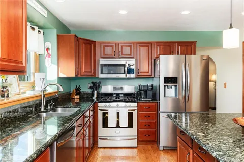 a kitchen with stainless steel appliances granite countertop a stove top oven a sink dishwasher a refrigerator and a microwave