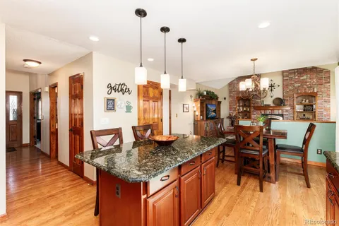 a kitchen with stainless steel appliances granite countertop dining table chairs and a view of living room