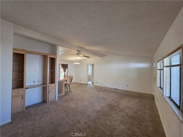 an empty room with chandelier fan and windows