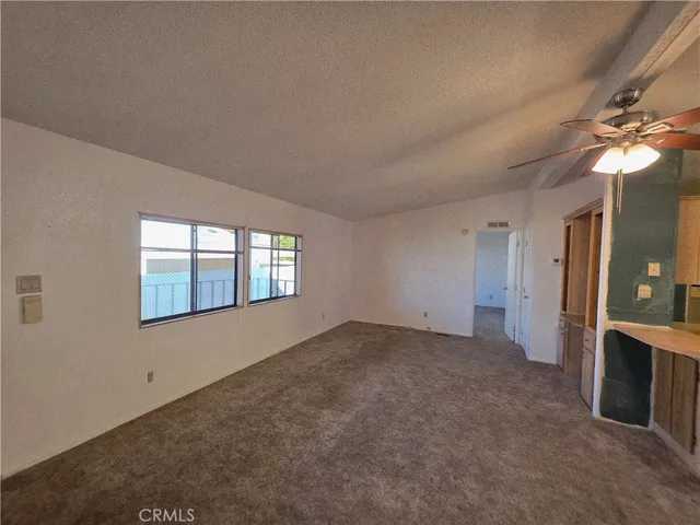 an empty room with chandelier fan and windows
