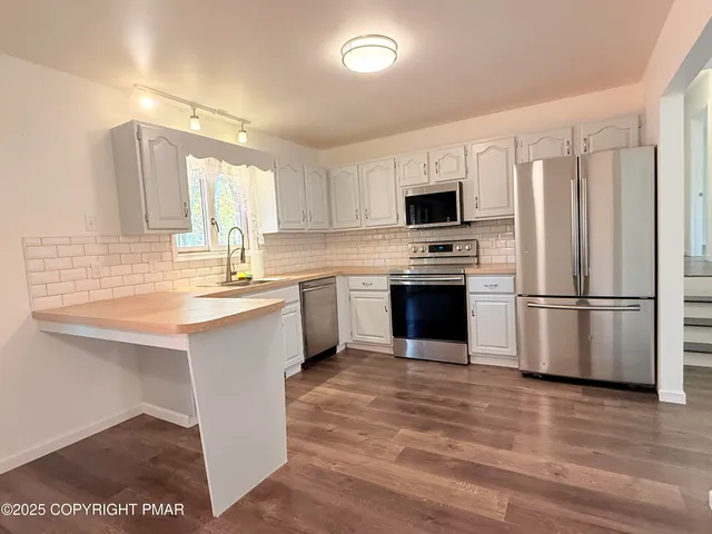 a kitchen with a sink cabinets stainless steel appliances and a window