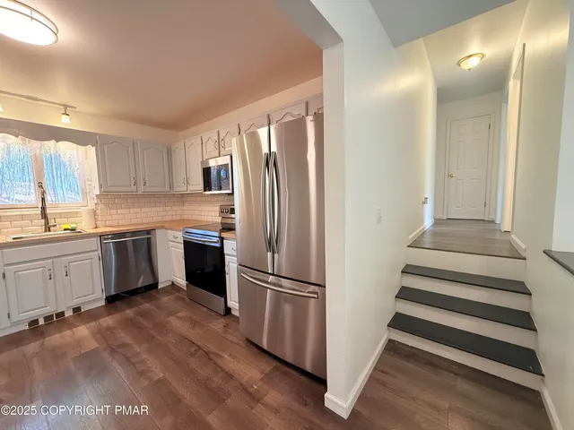 a kitchen with a refrigerator and white cabinets