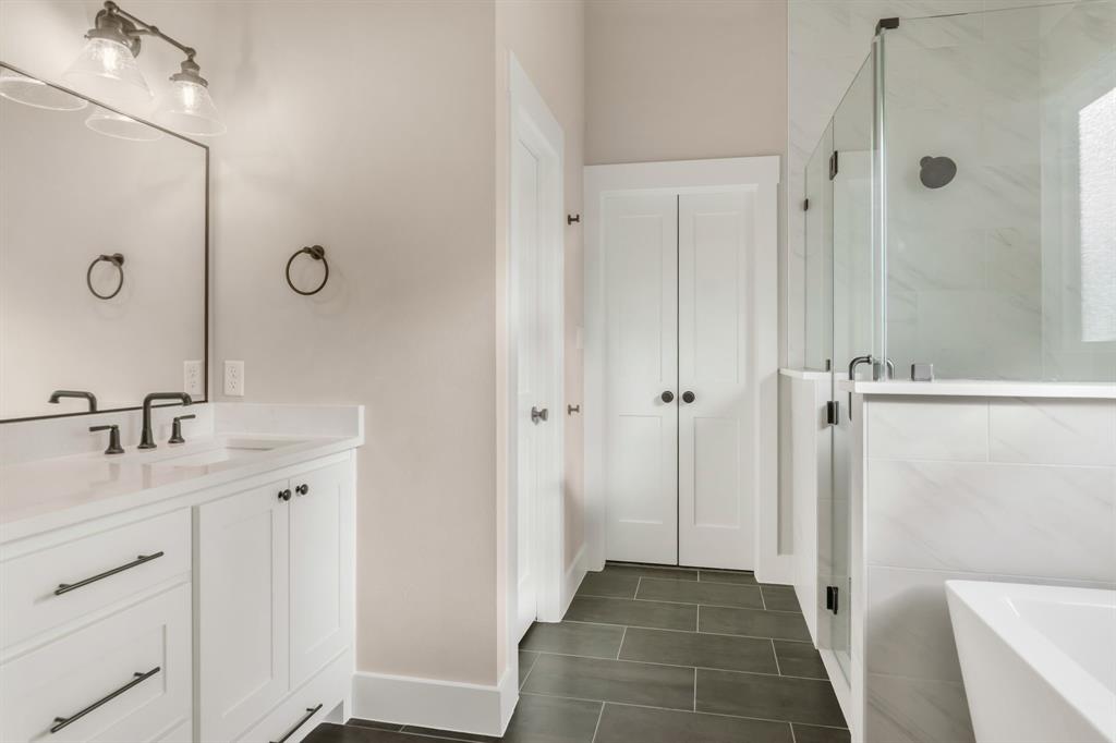 207 West 7th Street Justin, TX 76247 - Photo 21 of 40 a spacious bathroom with a granite countertop sink a mirror and a shower