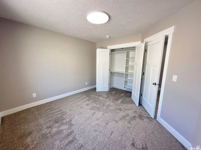 1171 West 2330 North Helper, UT 84526 - Photo 20 of 26 Unfurnished bedroom with a closet, carpet, and a textured ceiling