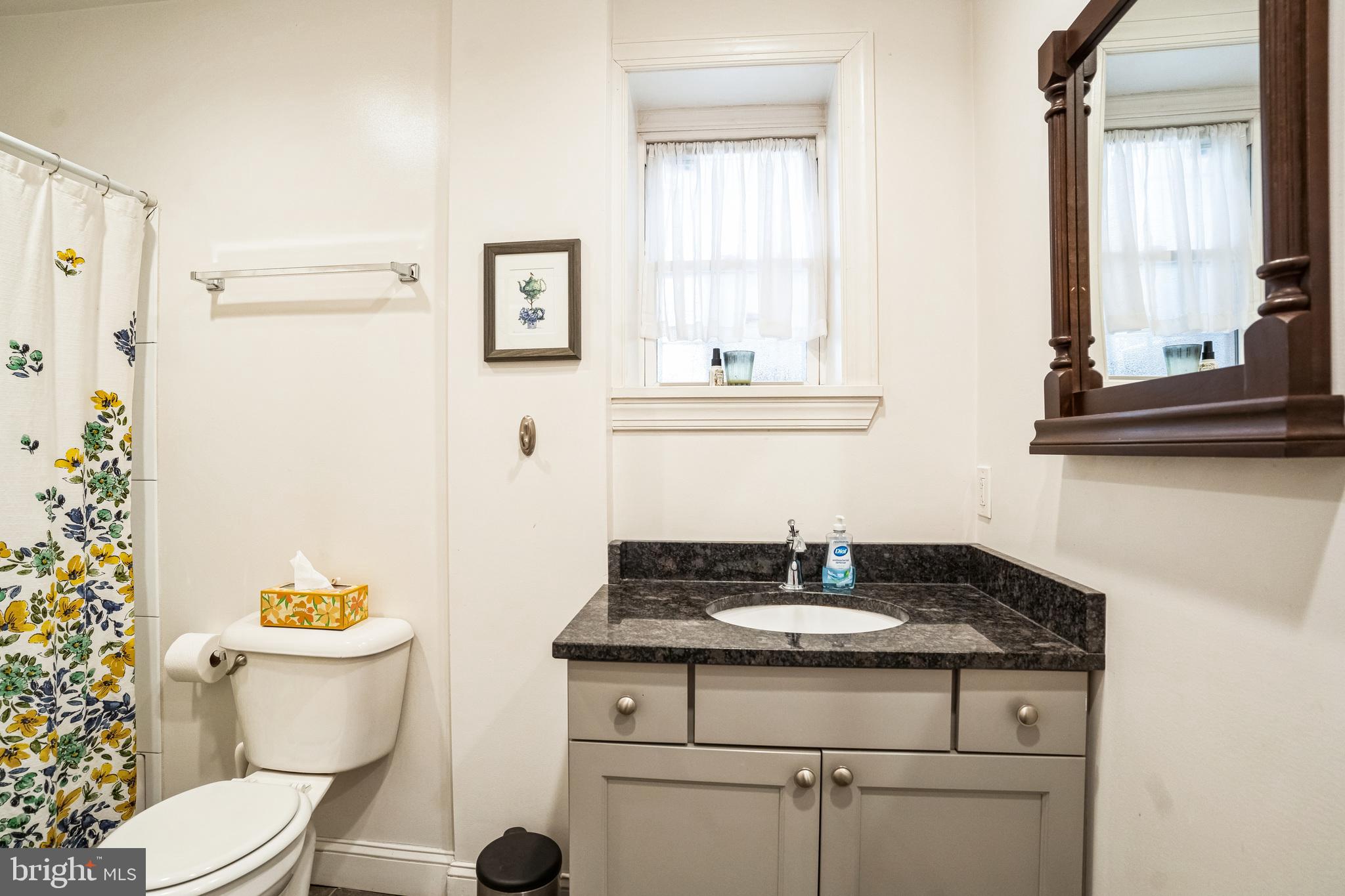 2124 Spruce Street, Unit 1R Philadelphia, PA 19103 - Photo 13 of 17 a bathroom with a granite countertop toilet sink and mirror