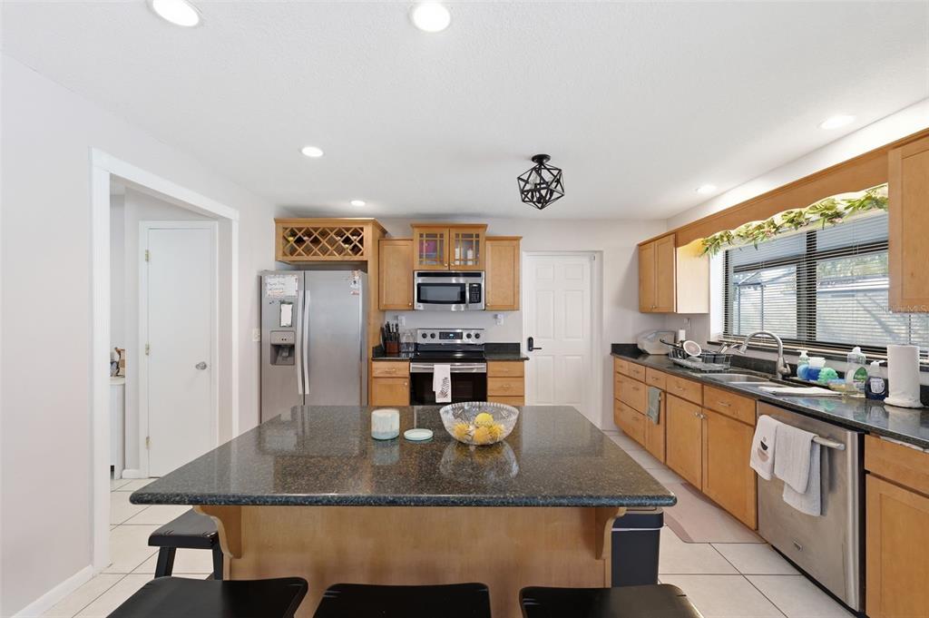 12935 Rain Forest Street Temple Terrace, FL 33617 - Photo 13 of 51 a kitchen with stainless steel appliances granite countertop a stove a refrigerator a sink dishwasher with a dining table and chairs