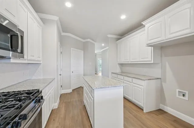 a kitchen with stainless steel appliances granite countertop a stove and a white cabinets