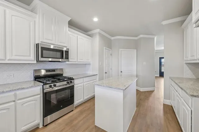 a kitchen with granite countertop a sink stove and white cabinets