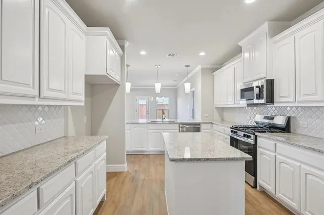 a kitchen with kitchen island granite countertop a sink a stove oven and white cabinets