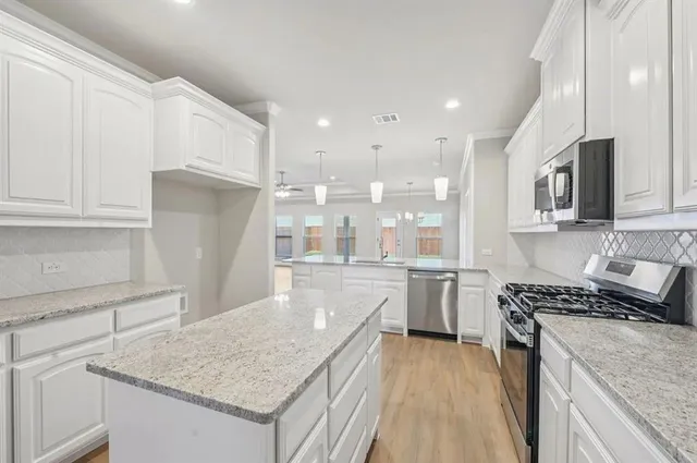 a kitchen with kitchen island granite countertop a sink stove and refrigerator