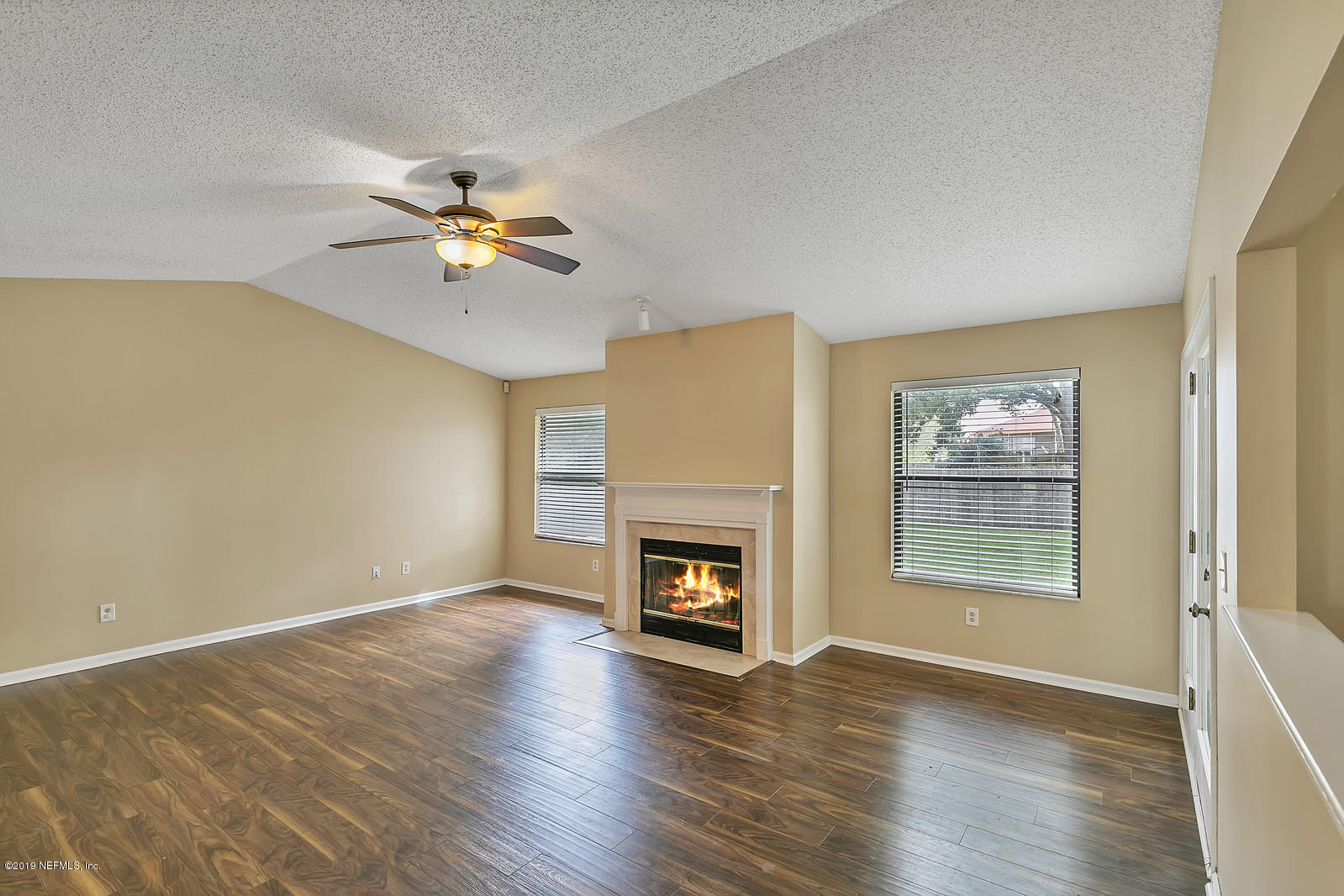 12436 Running River Road South Jacksonville, FL 32225 - Photo 4 of 25 an empty room with windows fireplace and wooden floor
