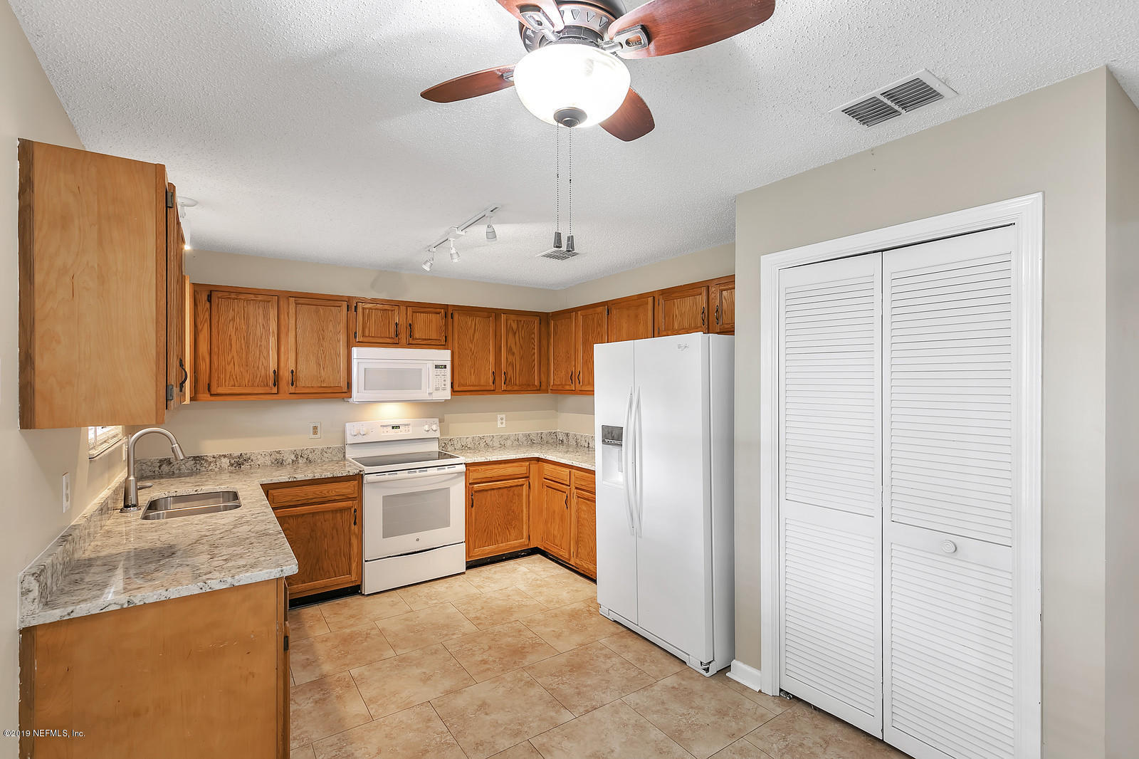 12436 Running River Road South Jacksonville, FL 32225 - Photo 7 of 25 a kitchen with stainless steel appliances granite countertop a refrigerator a sink dishwasher a stove and a dining table with wooden floor