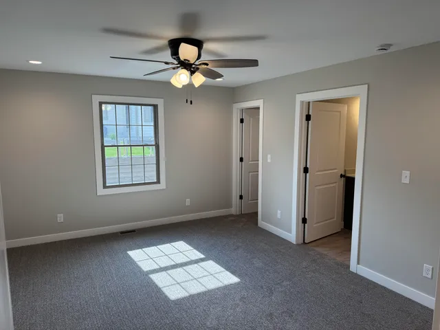 an empty room with windows and fan
