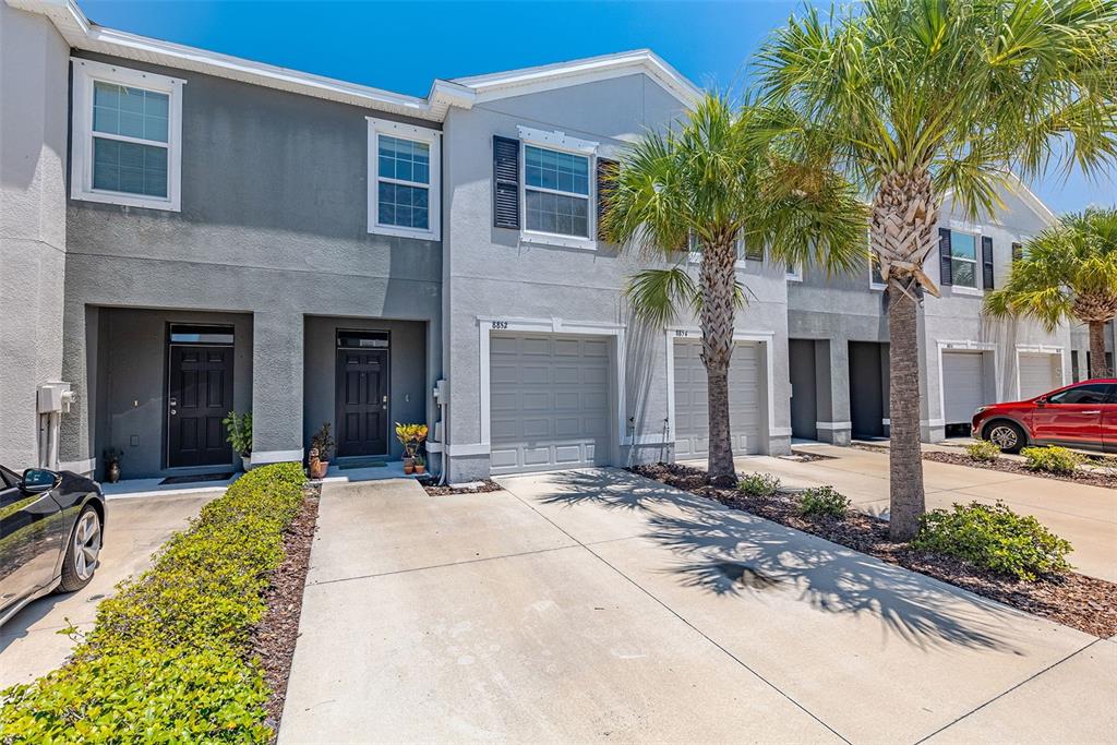 a view of a house with potted plants and a large tree