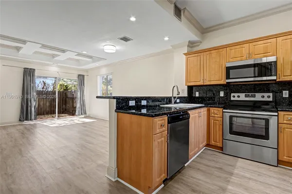 a kitchen with stainless steel appliances granite countertop a stove a sink and a microwave