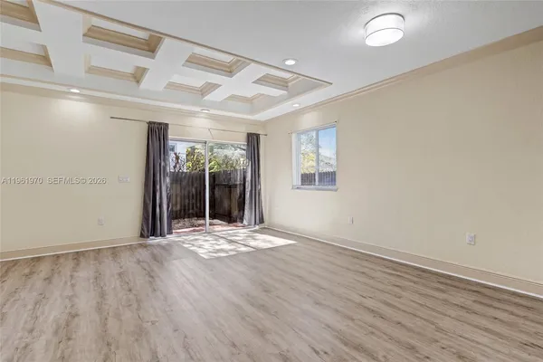 an empty room with wooden floor and a ceiling fan