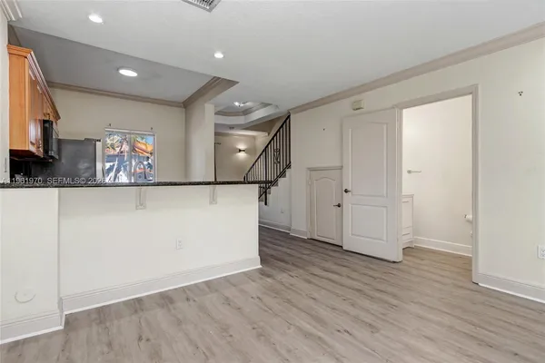 a view of an empty room with wooden floor and windows