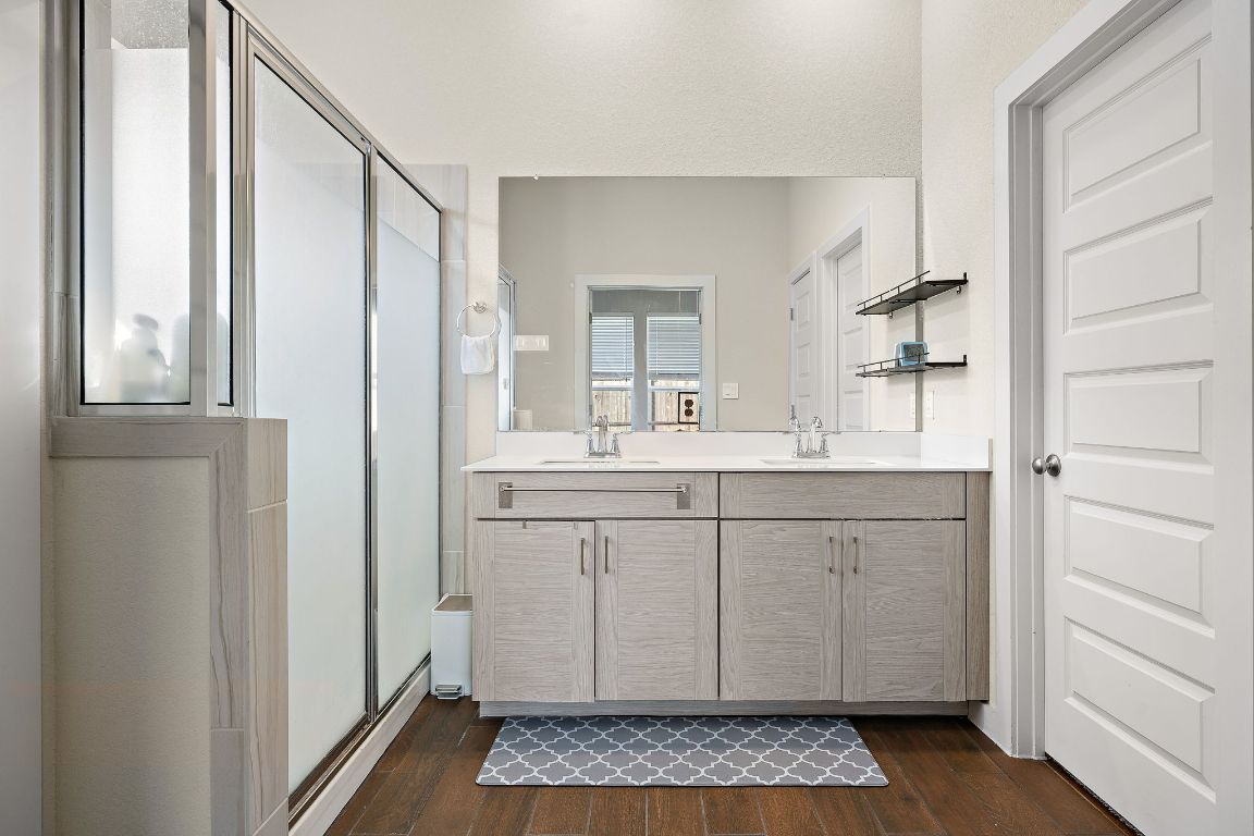 120 Upland Drive Georgetown, TX 78628 - Photo 11 of 21 Full bath featuring a stall shower, double vanity, and dark wood finished floors