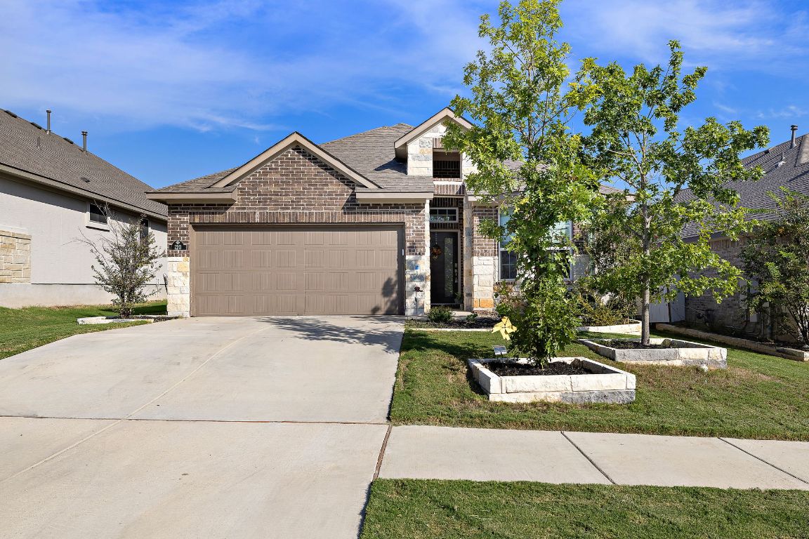 120 Upland Drive Georgetown, TX 78628 - Photo 2 of 21 View of front of property featuring brick siding, stone siding, driveway, a garage, and a front yard