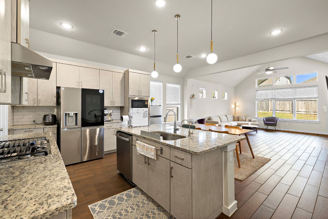 120 Upland Drive Georgetown, TX 78628 - Photo 21 of 21 Kitchen featuring light stone counters, an island with sink, pendant lighting, open floor plan, and appliances with stainless steel finishes