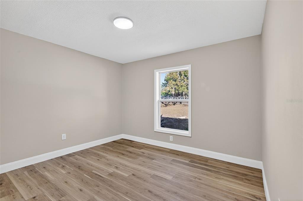 7078 South Threshold Point Homosassa, FL 34446 - Photo 20 of 75 an empty room with wooden floor and windows