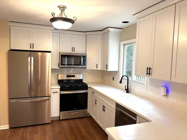 a kitchen with granite countertop a refrigerator stove top oven and sink