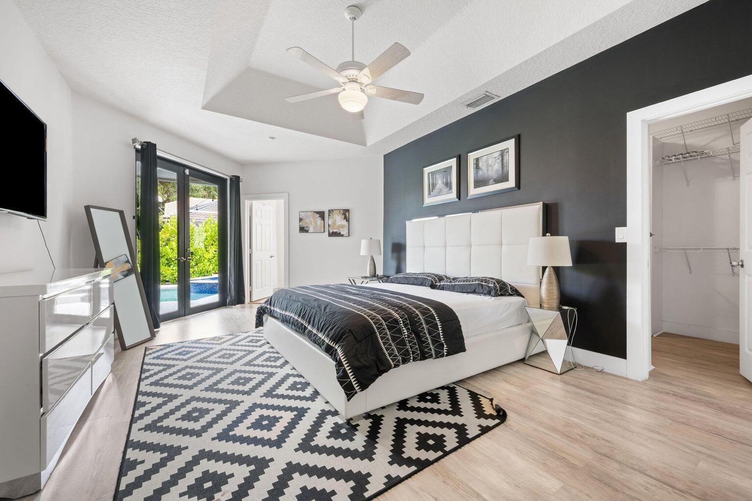 10982 Ravel Court Boca Raton, FL 33498 - Photo 18 of 43 a bedroom with a large bed a flat tv screen and a dresser