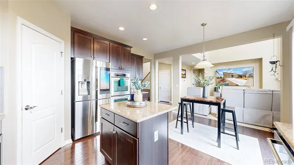 a kitchen with kitchen island a refrigerator a stove a dining table and chairs with wooden floor