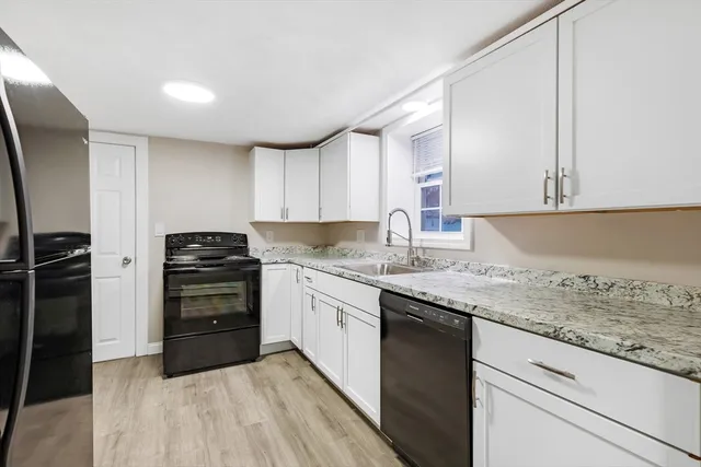 a kitchen with granite countertop a refrigerator stove and cabinets