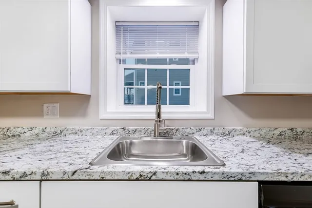 a kitchen with granite countertop a sink window and cabinets