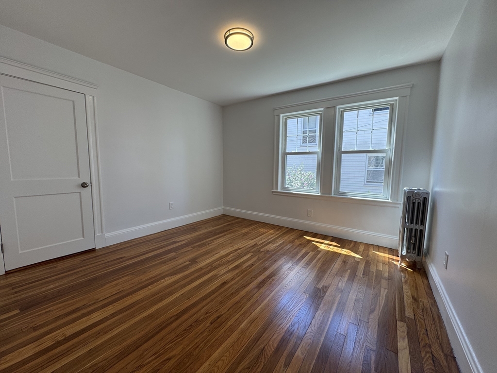 331 Vermont Street, Unit 1 Boston, MA 02132 - Photo 8 of 8 a view of an empty room with wooden floor and a window