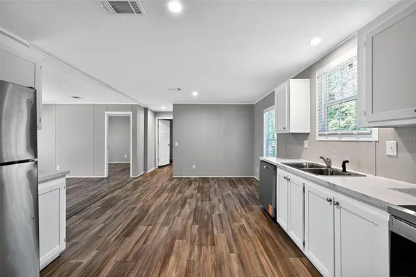 a kitchen with a sink wooden floor and stainless steel appliances
