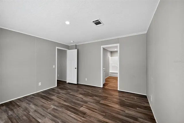 a view of an empty room with wooden floor and closet