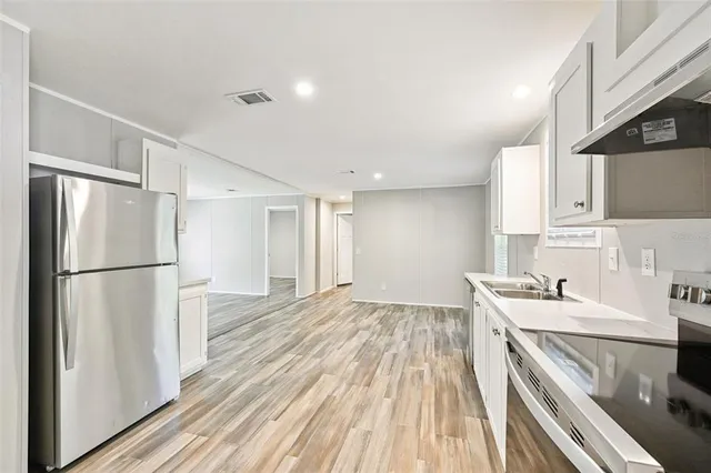 a kitchen with a sink a refrigerator and cabinets