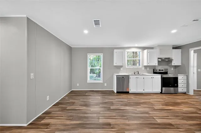 a large white kitchen with kitchen island a stove a refrigerator a sink and a stove with wooden floor