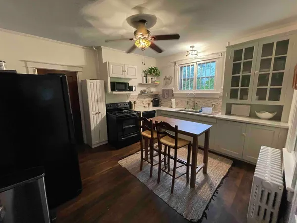 a kitchen with stainless steel appliances granite countertop a dining table chairs stove a refrigerator and a window
