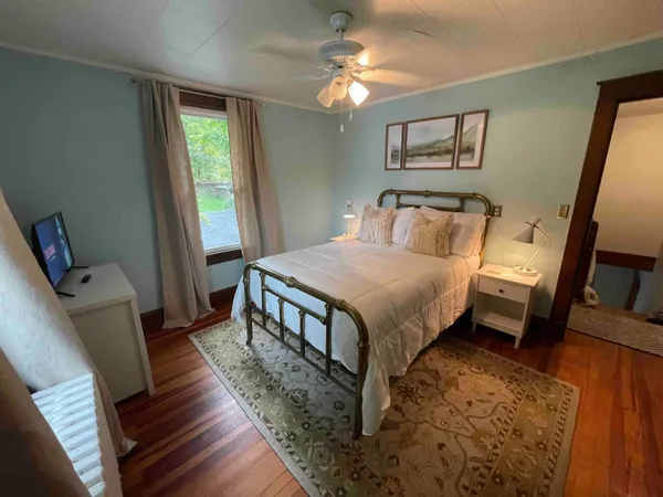 a bedroom with a bed a large window with wooden floor