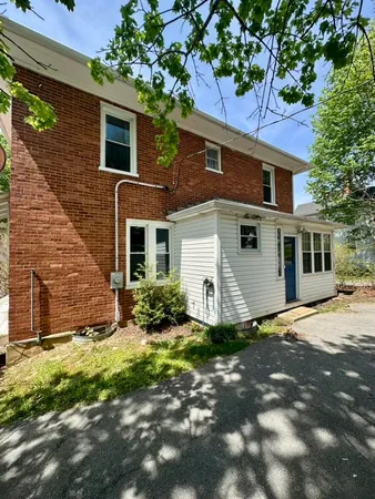 a view of a yard in front of a brick house with large windows
