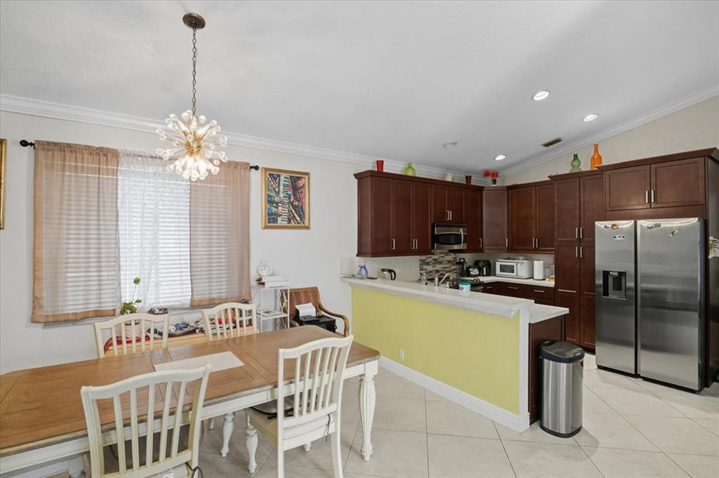 7631 Northwest 87th Terrace Tamarac, FL 33321 - Photo 17 of 23 a kitchen with a dining table chairs sink and refrigerator