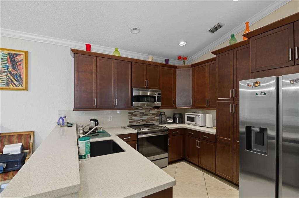 7631 Northwest 87th Terrace Tamarac, FL 33321 - Photo 18 of 23 a kitchen with stainless steel appliances granite countertop a refrigerator sink and stove