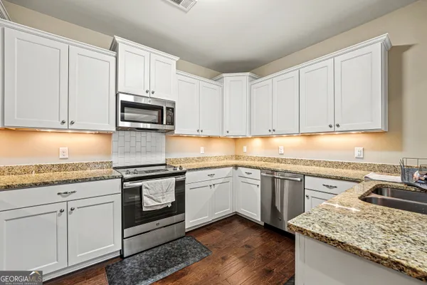 a kitchen with granite countertop cabinets stainless steel appliances and a counter space