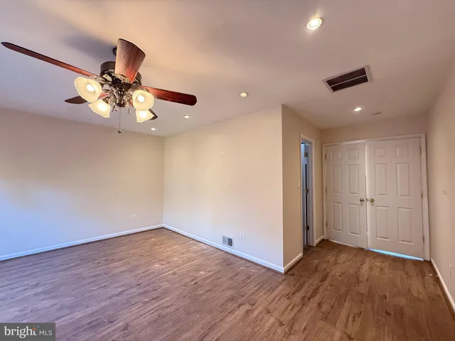a view of an empty room with window and kitchen view